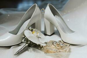 sida se, stängd kvinnors vit högklackade skor, parfym och brudens boutonniere. kvinnors engagemang ringa, bröllop begrepp foto