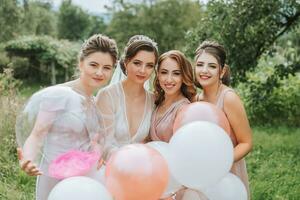 de brudtärnor se på de leende brud. de brud och henne roligt vänner fira en bachelorette fest utomhus i matchande klänningar. de brud och vänner på de gräs under de öppen himmel foto