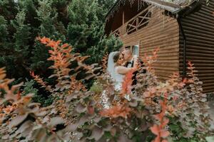 modern brudgum och söt brud i vit klänning med krona kramas i parkera, trädgård, skog utomhus. bröllop fotografi, porträtt av leende nygifta. foto