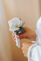 de brud är innehav en boutonniere tillverkad av ett orkide blomma. bröllop blommor foto