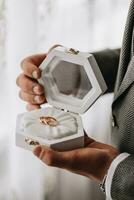 gyllene bröllop ringar i en gåva låda, i de händer av de brudgum, närbild foto