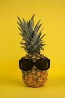 ananas med solglasögon på en gul bakgrund. sommar begrepp. foto