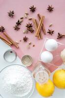 Ingredienser för bakning - ägg, mjöl, socker, kanel, stjärna anis, citron- på rosa bakgrund foto