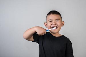 liten pojke som borstar tänderna i studiofoto foto