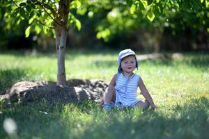 vacker baby pojke i barn trädgård poserar fotograf foto