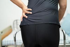 asiatisk dam patient smärta i ryggen, midjan och ortopediska ländryggen med rullator. foto