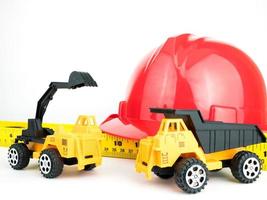 röd skyddshjälm med mekanisk grävare och lastbilsleksak, konstruktionskoncept