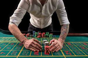en närbild vibrerande bild av grön kasino tabell med roulett, med de händer av croupier och flerfärgad pommes frites. foto