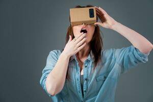 kvinna använder sig av en ny virtuell verklighet headsetet på grå bakgrund foto