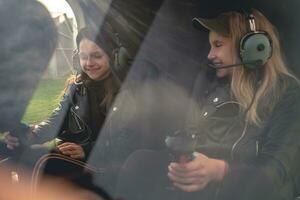 två leende mellan flickor i flygare headsets Sammanträde i helikopter cockpit foto