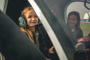 leende mellan flicka i pilot headsetet Sammanträde i helikopter cockpit foto