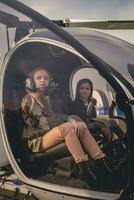 två drömmande mellan flickor på pilot säten i helikopter cockpit foto