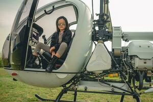 preteen flicka i speglad solglasögon Sammanträde i öppen helikopter cockpit foto
