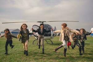 Lycklig tweenager flickor löpning på flygfält efter flygande i helikopter foto