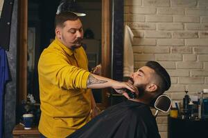 klient med stor svart skägg under skägg rakning i barberare affär foto