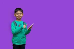 glad ung pojke i skjorta som pekar upp och håller armen vit och tittar på kameran över isolerad bakgrund och kopieringsutrymme foto