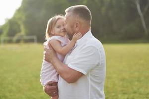 en söt liten flicka tillbringar tid med sin älskade farfar i parken foto