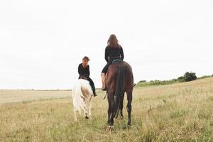 två unga vackra tjejer som rider på en häst på ett fält. de älskar djur och ridning foto