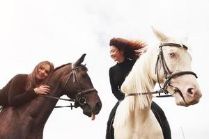 två unga vackra tjejer som rider på en häst på ett fält. de älskar djur och ridning foto