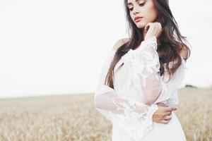 vacker flicka i ett veteområde i en vit klänning, en perfekt bild i stilen livsstil foto
