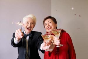 två vackra snygga mogna äldre kvinnor som firar nytt år. kul, fest, stil, firande koncept
