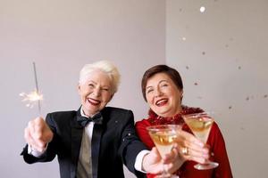 två vackra snygga mogna äldre kvinnor som firar nytt år. kul, fest, stil, firande koncept