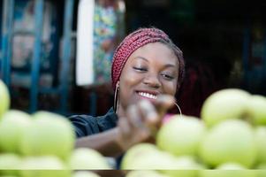 leende ung kvinna som väljer äpple på gatumarknaden. foto