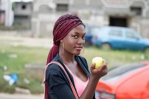 ung kvinna som håller ett äpple och tittar på kameran. foto