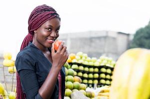 leende ung kvinna som håller en tomat. foto