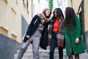 multietnisk grupp av tre glada kvinnor som går tillsammans utomhus