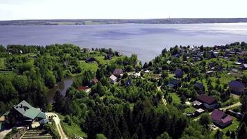 stuga stad på bakgrund blå sjö. klämma. topp se av en Land by i en skog område förbi de sjö foto