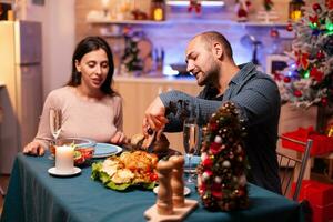 gift Lycklig par Sammanträde på dining tabell i xmas dekorerad kök njuter jul vinter- middag. romantisk glad Lycklig fira jul Semester. jultomten vintertid foto