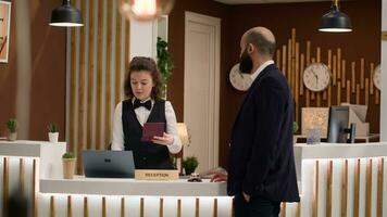 hotell concierge verifierande pass id för gäst Identifiering, framställning till fylla i registrering formulär. receptionist ser på referenser efter hälsning företag entreprenör i reception lobby. foto