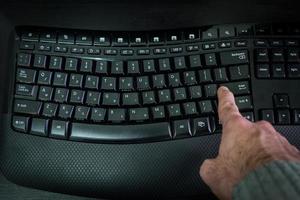 man som skriver på ett tangentbord med bokstäver på hebreiska och engelska foto