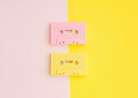 layout av retro rosa och gul audio kassett band på pastell rosa och gul bakgrund. kreativ begrepp av retro teknologi. 80 s estetisk. årgång audio kassett tejp aning. retro nostalgi. foto