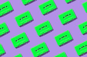 mönster tillverkad med retro grön audio kassett band på lila bakgrund. kreativ begrepp av retro teknologi. 80 s estetisk. årgång audio kassett tejp mönster aning. retro nostalgi. platt lägga. foto