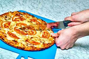 skärande nyligen beredd pizza med en kniv.klar till äta bakad pizza foto