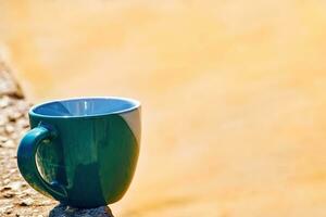grön keramisk kopp.kaffe, te, drycker på de gul strand sand foto