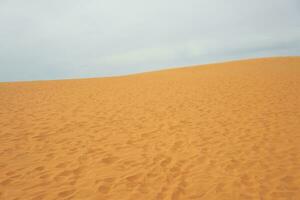 sand dyn i de öken- med moln i de bakgrund. foto