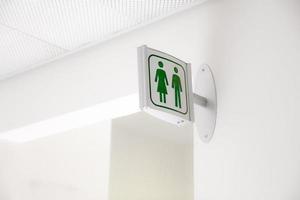 offentliga moderna vita och gröna toalettskyltar på vit vägg foto