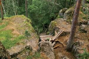 förstörd trä- trappa på ett övergiven väg i en berg skog foto