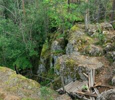 förstörd trä- trappa på ett övergiven väg i en berg skog foto