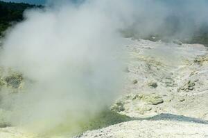 landskap av en fumarole fält på de backe av en vulkan är delvis dold förbi tät ångor foto