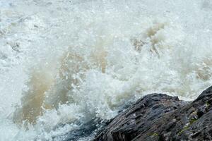 grumlig turbulent ström under en sten under hög vatten foto