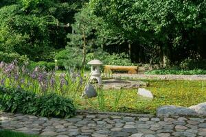 sten lykta på en små ö i de mitten av en damm i en japansk trädgård foto