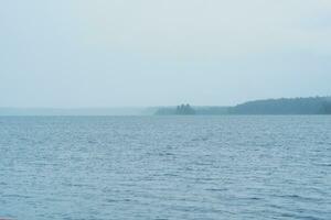naturlig landskap, omfattande grund sjö på en regnig dag, de skyfall döljer de avlägsen Strand foto