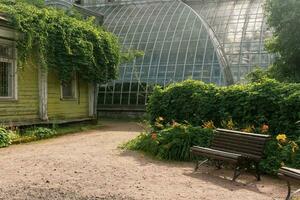 hörn av ett gammal botanisk trädgård med en enorm årgång växthus i de bakgrund foto