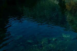 vågig vatten yta av en klar skog sjö med reflexion av bergen och himmel foto