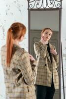 ung rödhårig kvinna i främre av en full längd spegel foto