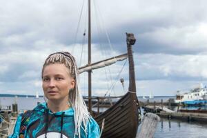 kvinna turist kommer i land efter segling på en modern kopia av ett gammal viking fartyg foto